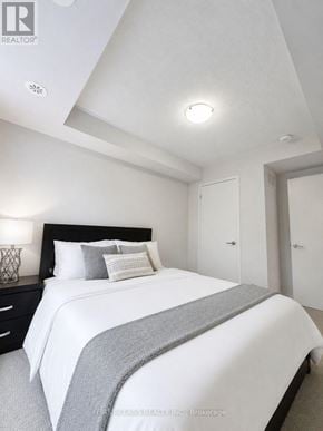 Toronto (New Toronto) townhouse for rent - A bedroom with a bed, nightstand, and two doors.