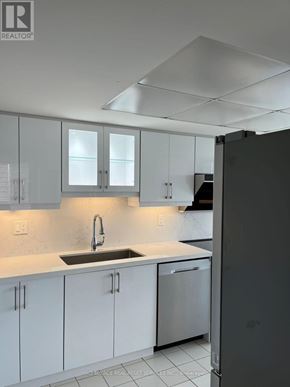 Toronto (Milliken) condo for rent - A kitchen with white cabinets and a black refrigerator.