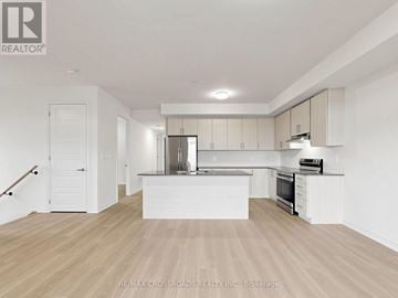 Clarington (Courtice) apartment for rent - A spacious kitchen with white cabinets and a wooden floor.