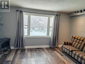 Orillia apartment for rent - A living room with a striped couch and a window showing a snowy scene outside.