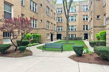 Oak Park apartment for rent - A courtyard with a bench and a tree in front of a brick building.