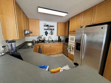Waianae apartment for rent - A kitchen with wooden cabinets and a stainless steel refrigerator.
