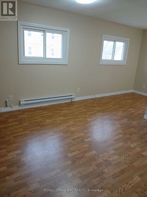 Niagara Falls (Downtown) fourplex for rent - A room with wooden floors and two windows.