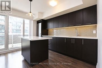 Toronto (Clanton Park) condo for rent - A kitchen with black cabinets and a white island.