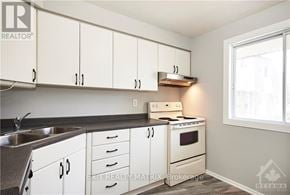 Ottawa townhouse for rent - A kitchen with white cabinets and a stove top oven.