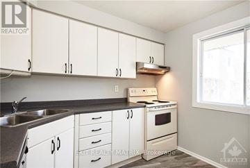 Ottawa townhouse for rent - A kitchen with white cabinets and a stove top oven.