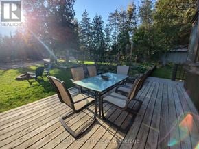 Collingwood apartment for rent - A wooden deck with a glass table and chairs is surrounded by trees.
