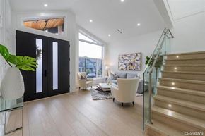 Surrey apartment for rent - A modern living room with a glass staircase and a large window.