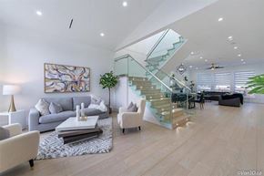 Surrey apartment for rent - A modern living room with a glass staircase and a grey sofa.