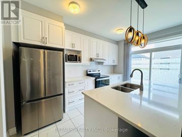 Ottawa townhouse for rent - A kitchen with a stainless steel refrigerator and white cabinets.