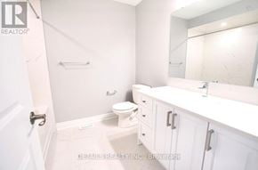 Ottawa townhouse for rent - A white bathroom with a toilet, sink, and mirror.