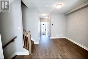 Ottawa townhouse for rent - A hallway with wood floors and white walls leading to a door.