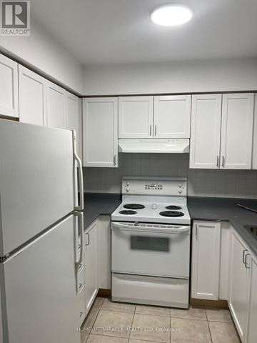 Toronto (Willowdale East) condo for rent - A white refrigerator is in a kitchen with white cabinets.