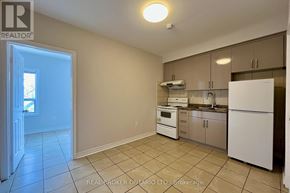 Toronto (Danforth) apartment for rent - A kitchen with white appliances and beige tiles.