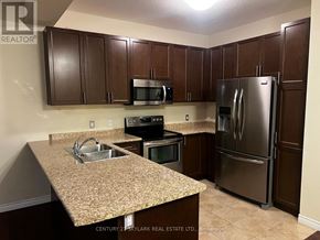 Hamilton townhouse for rent - A kitchen with brown cabinets and a granite countertop.