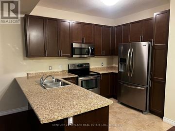 Hamilton townhouse for rent - A kitchen with brown cabinets and a granite countertop.