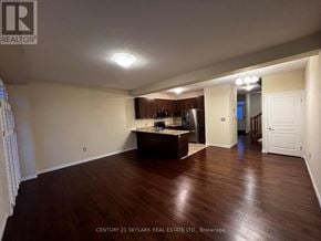 Hamilton townhouse for rent - A spacious room with wooden flooring and a kitchen area in the background.