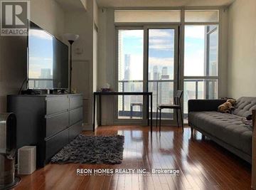 Toronto (Church-Yonge Corridor) condo for rent - A living room with a black couch and a television.