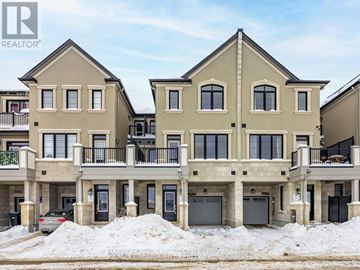 Mississauga (Churchill Meadows) townhouse for rent - A large, two-story house with a balcony and a garage is surrounded by snow.
