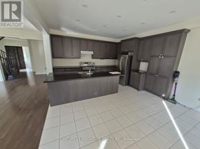 Whitby apartment for rent - A modern kitchen with dark brown cabinets and a white tiled floor.