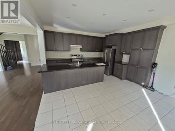 Whitby apartment for rent - A modern kitchen with dark brown cabinets and a white tiled floor.