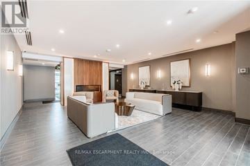 Hamilton (Waterdown) condo for rent - A spacious living room with a white sofa set and a wooden accent wall.