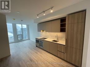 Toronto (Waterfront Communities) condo for rent - A modern kitchen with wooden cabinets and a large window.