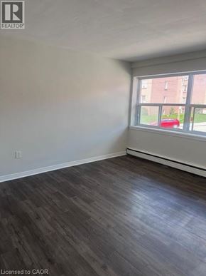 Hamilton apartment for rent - A room with wooden flooring and a window overlooking a red car and a building.