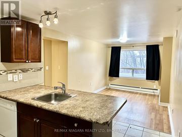 St. Catharines (Glendale/Glenridge) condo for rent - A kitchen with a granite countertop and a window with black curtains.