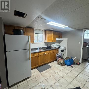 Clarington (Bowmanville) apartment for rent - A kitchen with a refrigerator, oven, and a bag of trash on the floor.