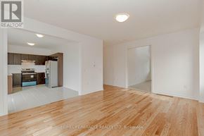 Southgate apartment for rent - A spacious room with wooden flooring and white walls, with a kitchen visible in the background.