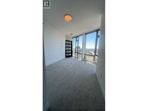 Vancouver apartment for rent - A room with a carpeted floor and a large window overlooking a cityscape.