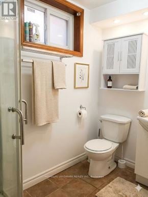 Toronto (Steeles) apartment for rent - A white toilet sits in a small bathroom with a white cabinet and a window.