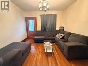Windsor apartment for rent - A living room with a grey couch, a glass coffee table, and a chandelier.