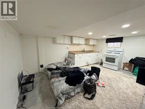 Windsor apartment for rent - A bedroom with a bed, a desk, and a kitchen area in the background.