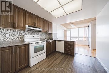 Brampton (Queen Street Corridor) condo for rent - A kitchen with wooden cabinets and a white stove top oven.