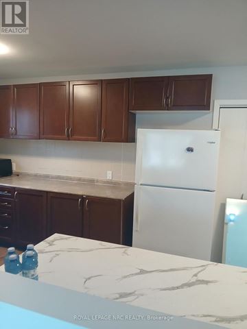 Niagara Falls (Morrison) apartment for rent - A white refrigerator in a kitchen with brown cabinets.