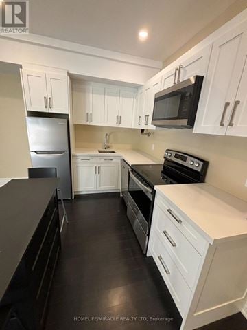 Toronto (Edenbridge-Humber Valley) apartment for rent - A kitchen with white cabinets and black appliances.