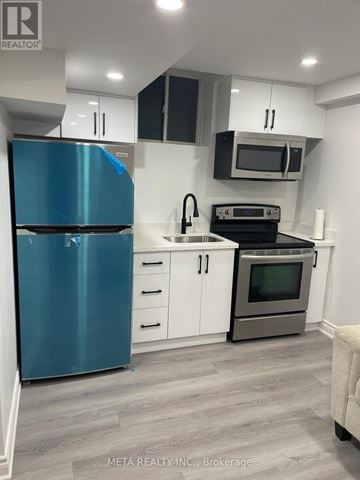 Whitchurch-Stouffville (Stouffville) apartment for rent - A blue refrigerator is in a kitchen with white cabinets and a microwave above the stove.