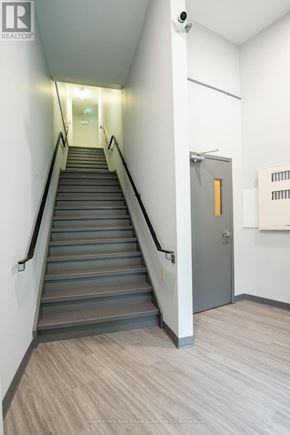 Stratford multi-family for rent - A staircase with a metal railing and a grey door at the top.