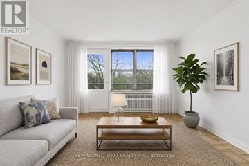 Toronto (Rosedale-Moore Park) condo for rent - A living room with a grey couch, a coffee table, and a large window with white curtains.
