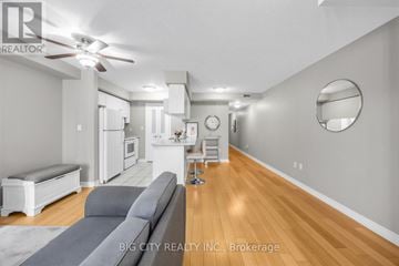 Toronto (Leaside) townhouse for rent - A living room with a grey couch and a white kitchen in the background.