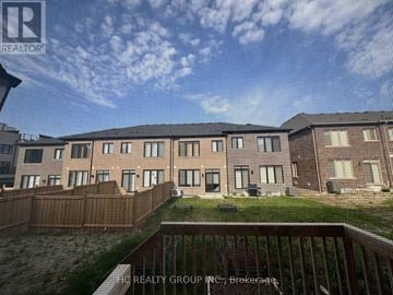 Markham (Angus Glen) townhouse for rent - A building complex with a fence and a grassy area in front.