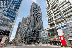 Toronto (Mount Pleasant West) condo for rent - A tall building with a glass facade stands in front of a street with other buildings.