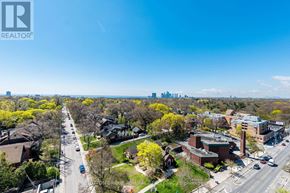 Toronto (High Park North) condo for rent - A street view of a residential area with houses on both sides and a clear blue sky above.