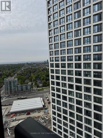 Toronto (Islington-City Centre West) condo for rent - A living room with a couch and a window overlooking a cityscape.