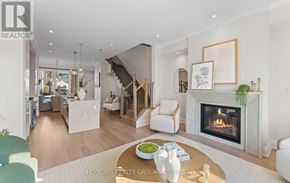 Mississauga (Mineola) townhouse for rent - A modern living room with a fireplace and a dining area in the background.