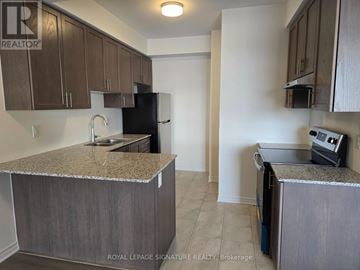 Brampton (Northwest Brampton) townhouse for rent - A kitchen with brown cabinets and granite countertops.