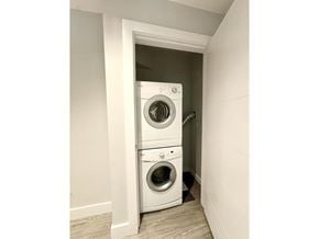 Surrey apartment for rent - A white dryer and washer are stacked in a small alcove.