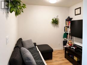 Kitchener condo for rent - A living room with a couch, a television, and a plant on the wall.